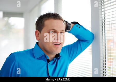 Cheerful business man leaning against window Stock Photo