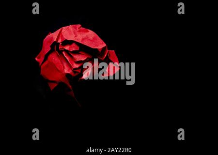 A scrap of crumpled paper on a black background with hard light and shadow. Stock Photo