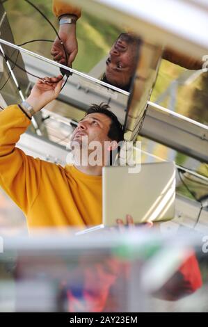 Engineer using laptop and connecting wires at work place Stock Photo