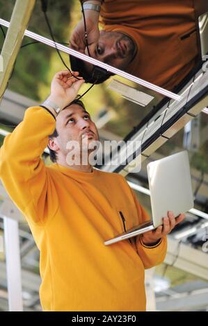 Engineer using laptop and connecting wires at work place Stock Photo