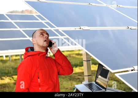 Engineer working with laptop by solar panels Stock Photo