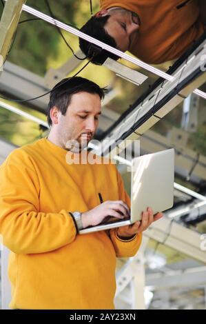 Engineer using laptop and connecting wires at work place Stock Photo