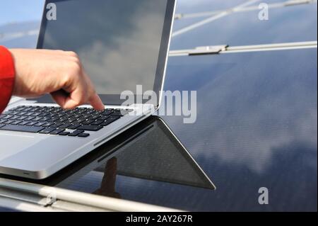Pressing enter button on laptop at  photovoltaic solar panels Stock Photo