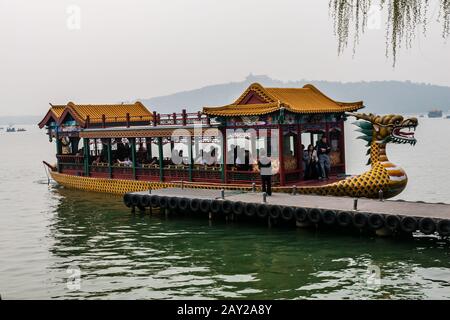 A richly decorated wooden cruise boat with tourists moored at a pier on the Kunming Lake, Beijing Stock Photo
