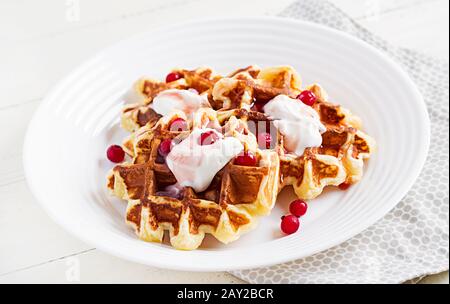 Traditional belgian waffles with berries, sour cream and jam on white wooden table. Stock Photo