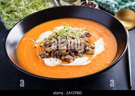 Delicious cream of pumpkin soup with roasted forcemeat made of beef minced meat in a bowl on a dark table. Thanksgiving Day. Stock Photo