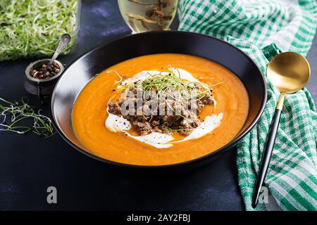 Delicious cream of pumpkin soup with roasted forcemeat made of beef minced meat in a bowl on a dark table. Thanksgiving Day. Stock Photo
