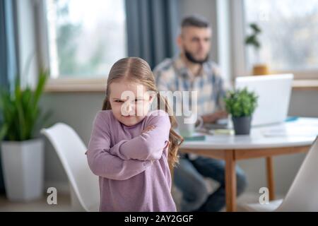 Offended little girl standing in the middle of the room. Stock Photo
