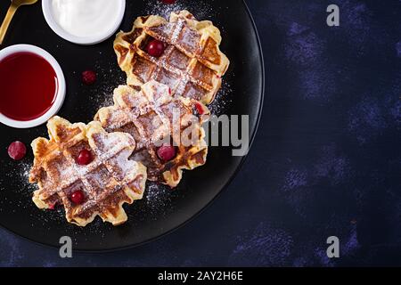 Traditional belgian waffles with berries, sour cream and jam on dark table. Top view, overhead Stock Photo