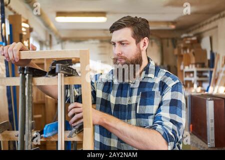 Hipster carpenter sorts screw clamps in the joinery or joinery Stock Photo