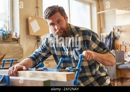 Hipster carpenter as a furniture maker works with a wooden workpiece on a vice Stock Photo