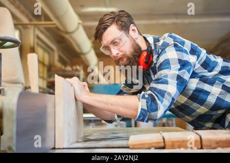 Apprentice carpenter works on the planer in the joinery Stock Photo