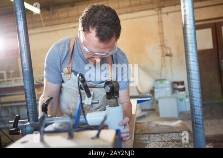 Carpenter in training works with wood on the staking machine Stock Photo