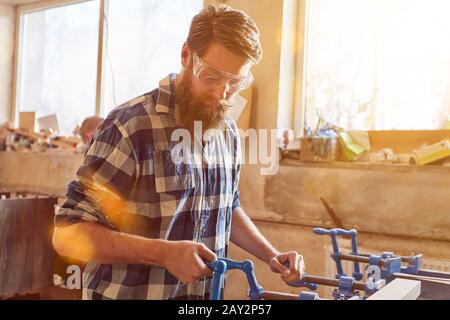 Carpenter with safety glasses works on a vice in carpentry Stock Photo