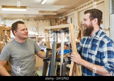 Carpenter apprentice and instructor in the carpentry with many screw clamps Stock Photo