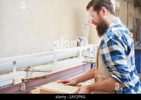 Carpenter with safety glasses when sanding wood on the grinding machine Stock Photo