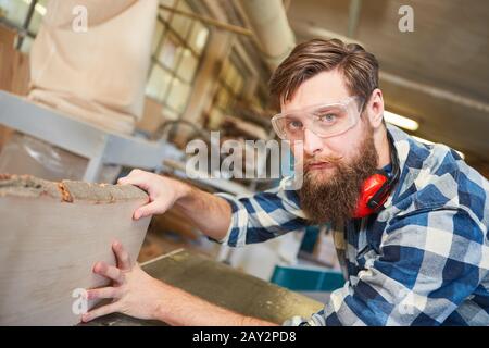 Hipster carpenter with beard training while planing on the planing machine Stock Photo
