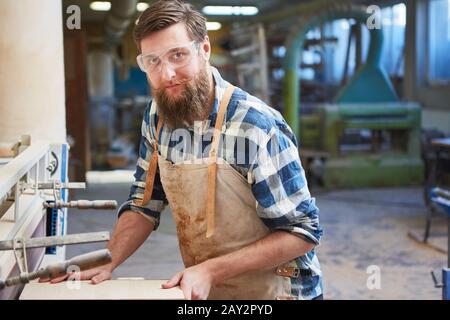 Carpenter apprentice as a furniture maker works with wood on the grinding machine Stock Photo