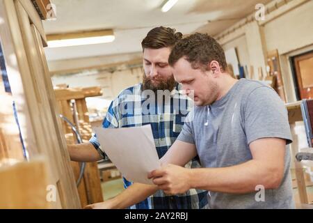 Carpenter team with order on a sheet of paper in the carpentry Stock Photo