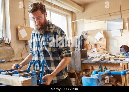Carpenter works as a furniture maker on a wood workpiece in the carpentry Stock Photo
