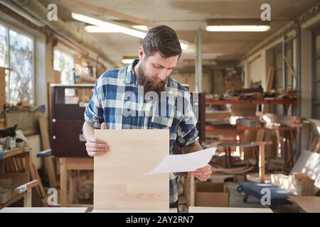 Carpenter with order on a sheet of paper in furniture making Stock Photo