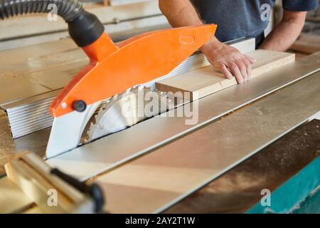Craftsman pushes wood board on the circular saw in the carpentry or joinery Stock Photo