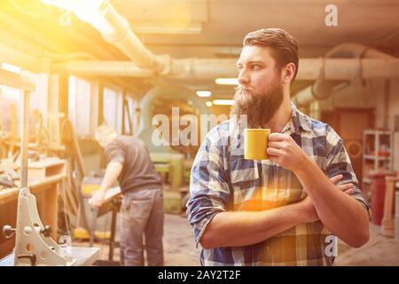 Self-employed hipster carpenter drinking coffee in the workshop Stock Photo