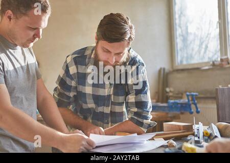 Two carpenters with order on a sheet of paper in the carpentry shop Stock Photo