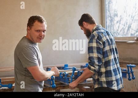 Carpenters work together as furniture makers on vices in the carpentry workshop Stock Photo