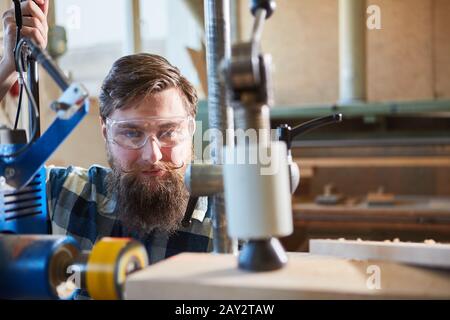 Hipster carpenter operates a drill with laser display in the carpentry Stock Photo