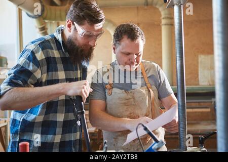 Carpenter apprentice with order on a sheet of paper in the joinery Stock Photo