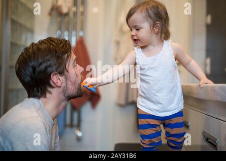 Girl brushing dads teeth Stock Photo