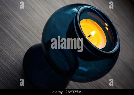 Home cozy: Blue glass candle holder with warming candle on the table Stock Photo