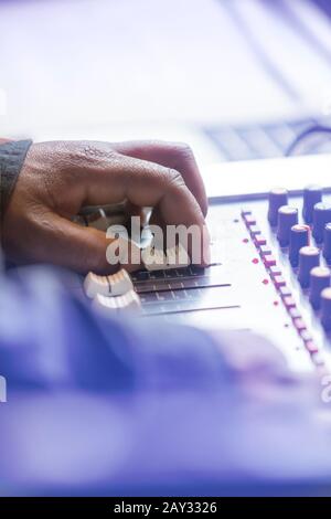 Sound engineers hand on mixing desk slider. Stock Photo