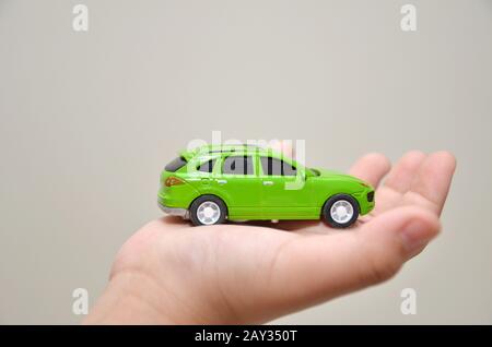 Green toy car on a right hand Stock Photo