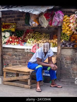 Johannesburg, South Africa , 4 October - 2019: Man sits beside his Fruit and vegetable stall in township. Stock Photo