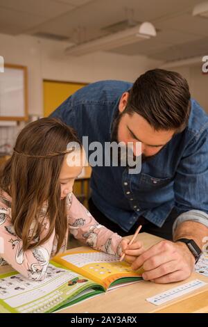 Teacher with girl in classroom Stock Photo