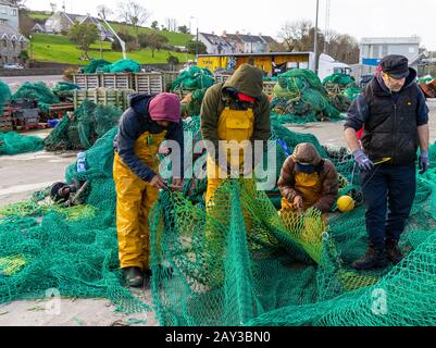 4 fishermen mending nets in union hall harbour ireland Stock Photo