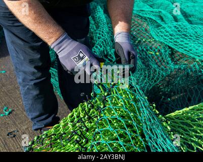 Close up of fisherman mending a fishing net. Stock Photo