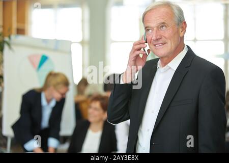 Elderly businessman in the office is talking on his smartphone Stock Photo