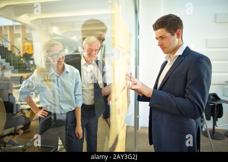 Man in the office looks at notes and charts on a glass wall Stock Photo
