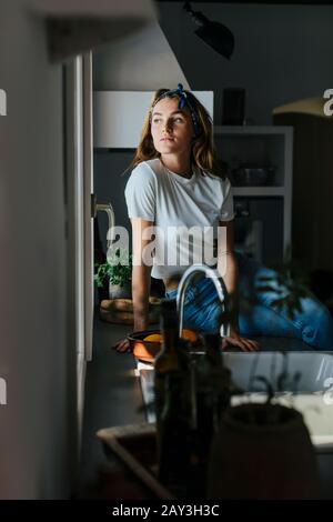 Woman looking through kitchen window Stock Photo