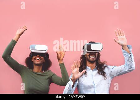 Happy couple using virtual reality headset outdoor - Trendy people having fun with innovated vr googles technology Stock Photo