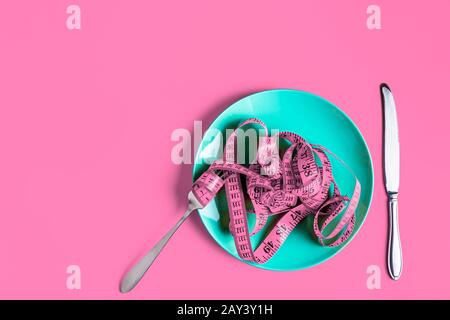 Closeup shot of a pink measuring tape and silverware- diet, weight loss  concept Stock Photo by wirestock