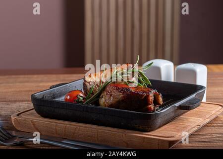 Grilled beef tenderloin with a sprig of rosemary and tomato. On a wooden table. Copy space Stock Photo