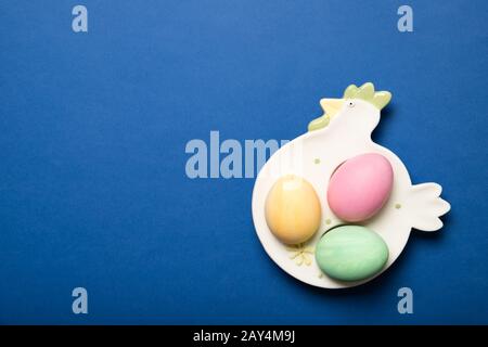 Beautiful Easter eggs on a plate on a blue background, Place for text, Top view, Stock Photo