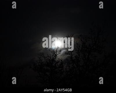 Snow moon peeping through the clouds, Stock Photo