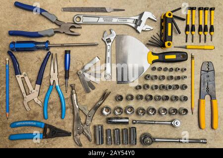 Flat lay photograph of a variety of tools displayed on a concrete garage floor Stock Photo