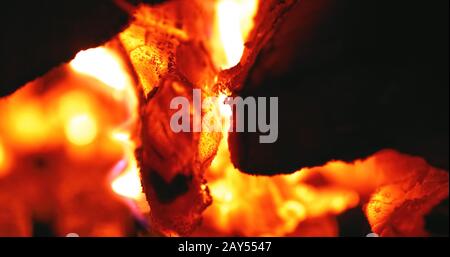 burning red fire and smoldering charcoal close-up, fire flame abstract sparkle black and orange smoke background, selective focus, cracks Stock Photo