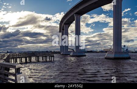 Dock and a large bridge on the Elizabeth River with storm clouds rolling in from the distance Stock Photo